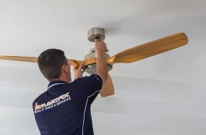 Electrician installing ceiling fan in home