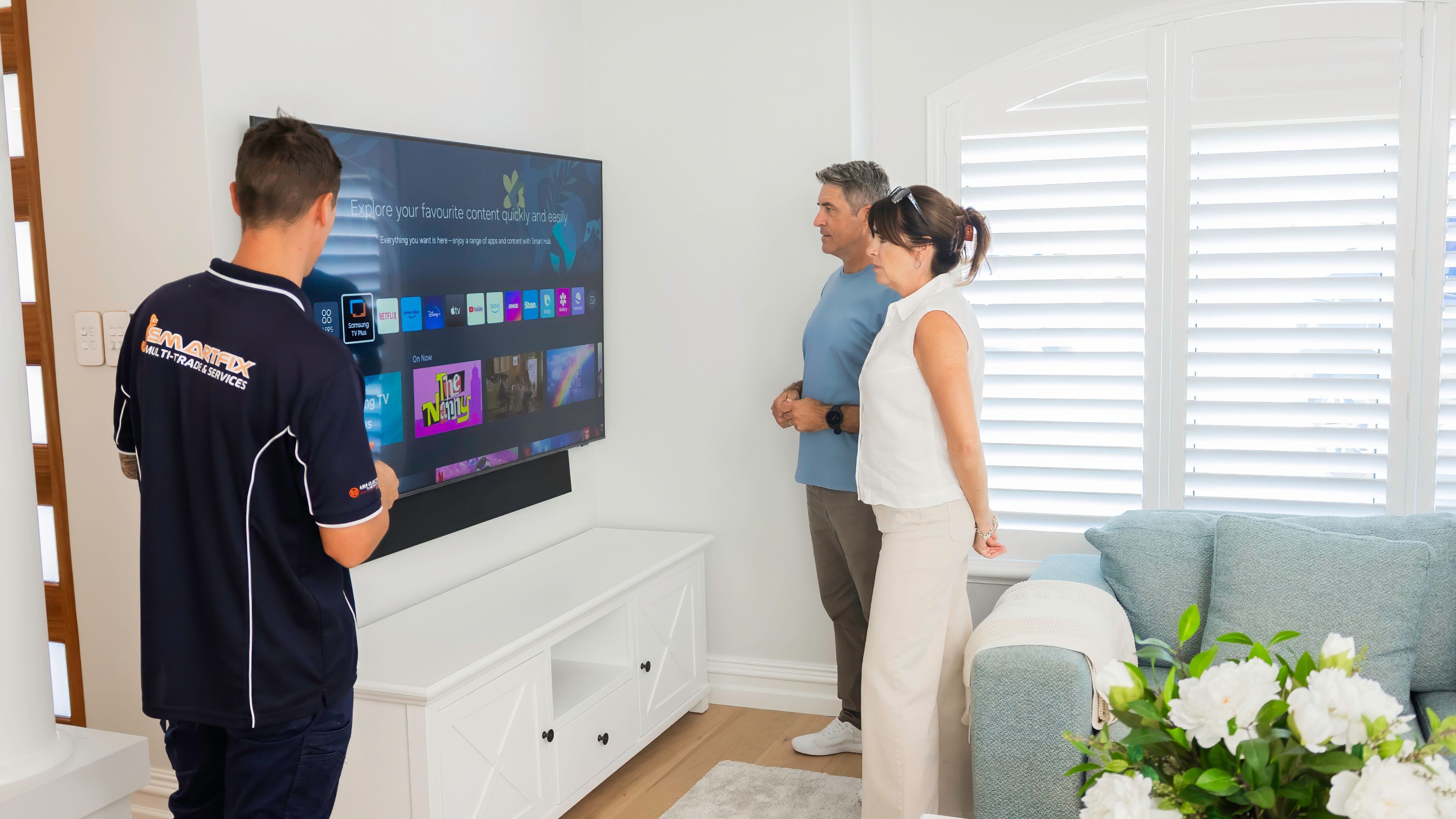 Peth electrician finishing TV wall mount. Showing customers how to use and set up Apple TV