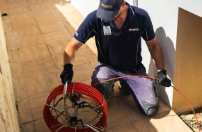 Plumber using a drain snake to diagnose a blocked drain