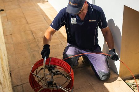 Plumber using a drain snake to diagnose a blocked drain